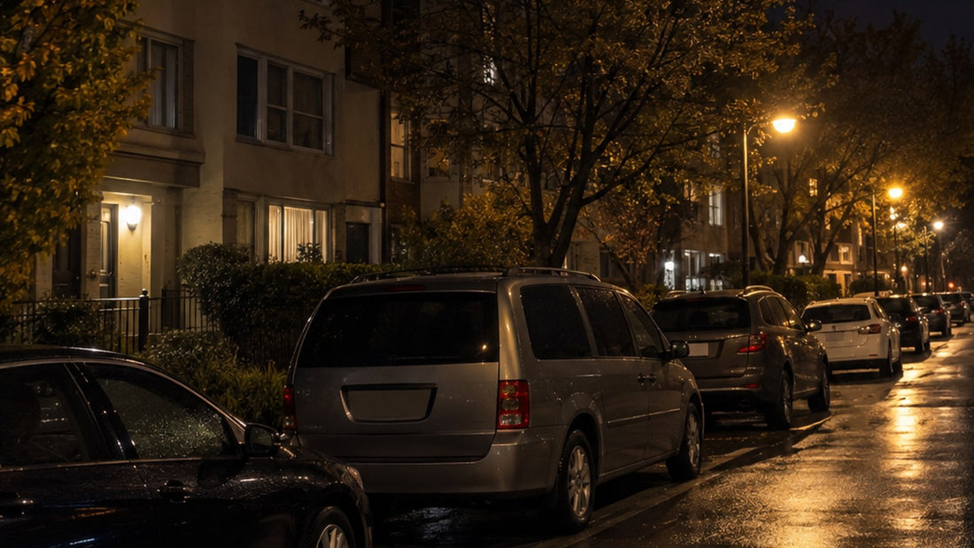 Plain grey minivan parked among other cars on a quiet city street at night